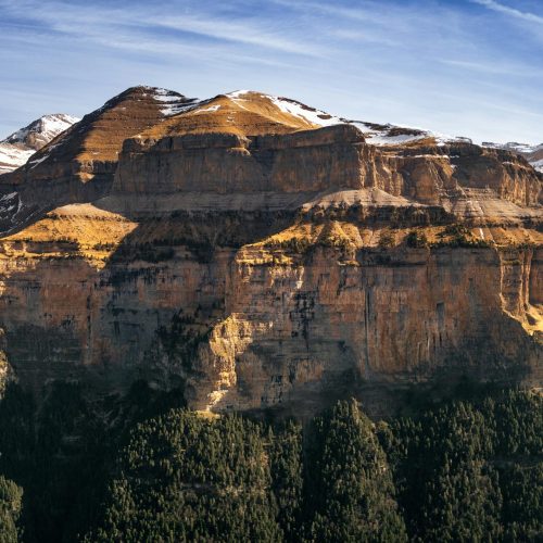 Stunning view of Ordesa Valley's massive cliffs and snowy peaks, showcasing nature's grandeur.